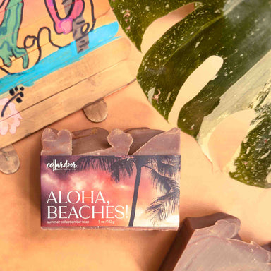 Bar of soap with 'Aloha, Beaches!' packaging on a beach-themed background