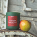 Green candle labeled 'Autumn Apple Fest' next to a red and green apple on a metal surface.