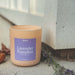 Candle with a lavender pumpkin label on a concrete surface with dried lavender and leaves.