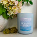 Candle labeled 'Morning Dew' with flowers and decorative elements in the background