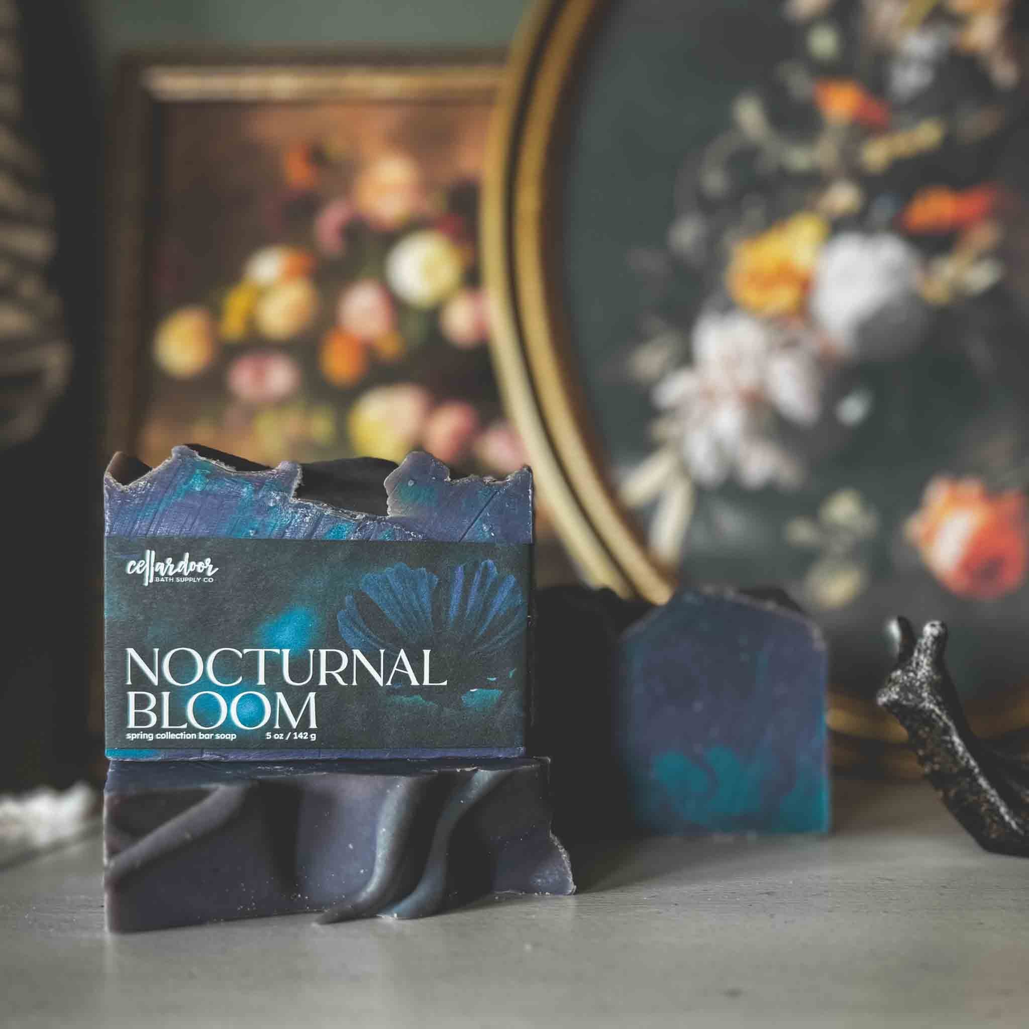 Bar of soap named 'Nocturnal Bloom' in front of a decorative still life painting.
