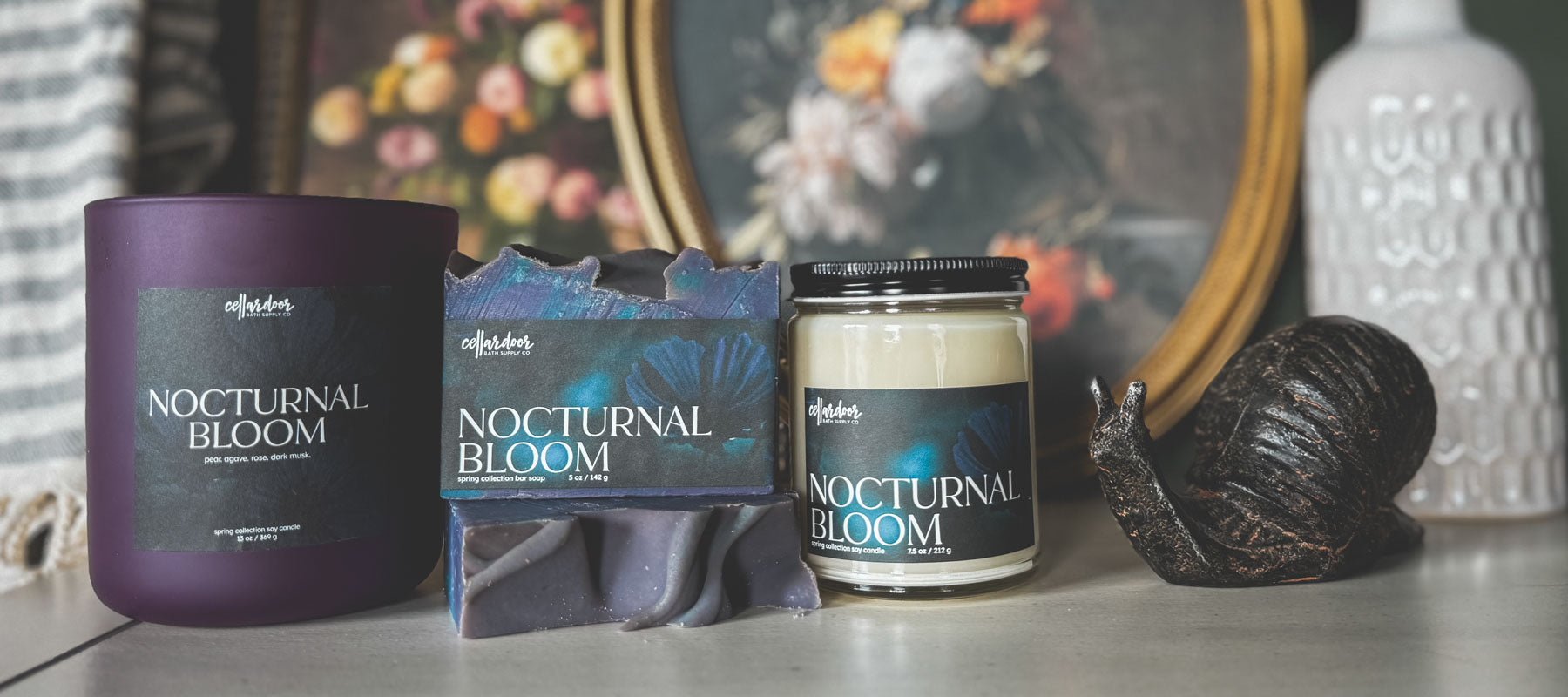 Candle and packaging labeled 'Nocturnal Bloom' on a surface with decorative items in the background.